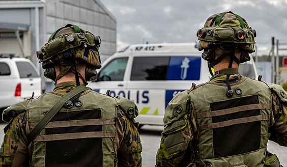 varusmiehiä selkä kameraan päin, taustalla poliisiauto